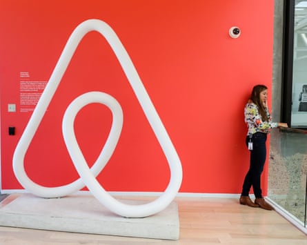 Airbnb’s looped white on red logo, next to woman talking on telephone