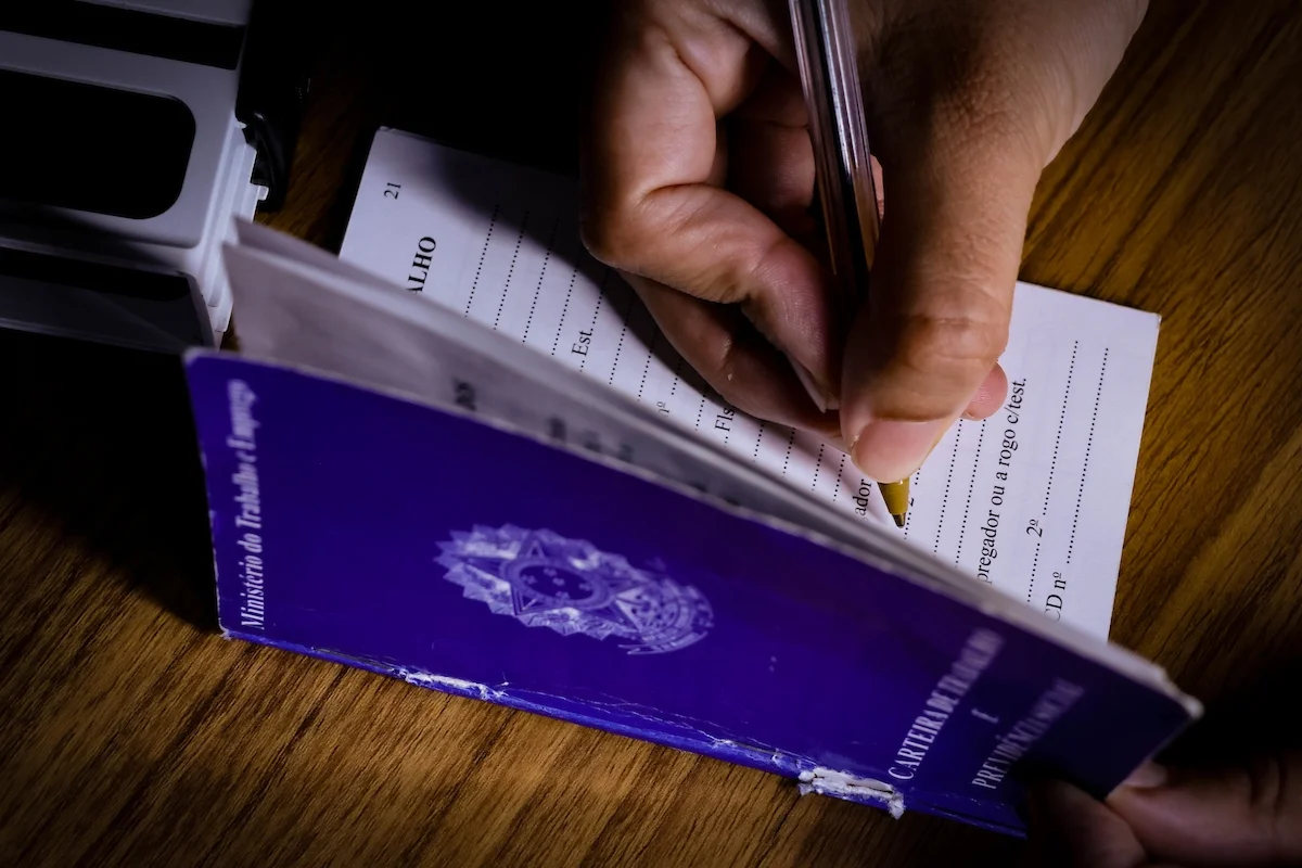 foto colorida de uma pessoa assinando carteira de trabalho - Metrópoles