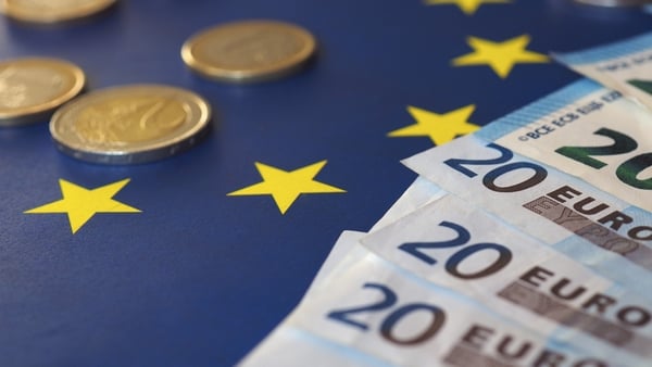 stock image of euro notes and coins on a EU flag