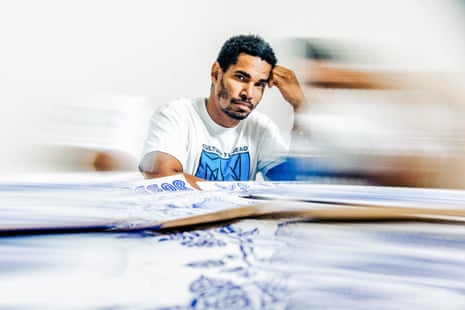 Artist Luis Manuel Otero Alcántara rests his hand on his head amid his blue-inked drawings