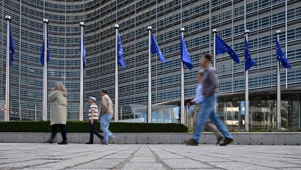 Pedestrians walk past the Berlaymont building, the EU Commission headquarters, in Brussels